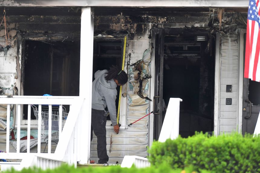 An investigator takes measurements Monday near an entrance to the Gabriel House assisted living facility following a fire that killed nine people in Fall River, Massachusetts.