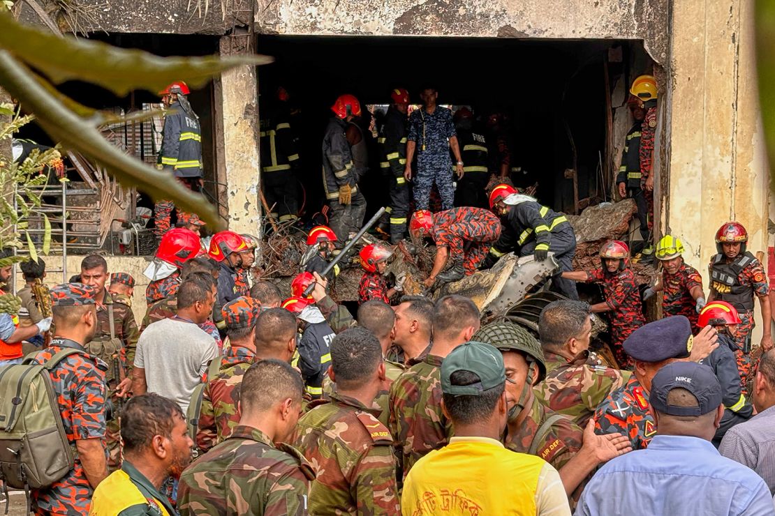 Firemen check the wreckage of the air force training aircraft that crashed onto the school campus.