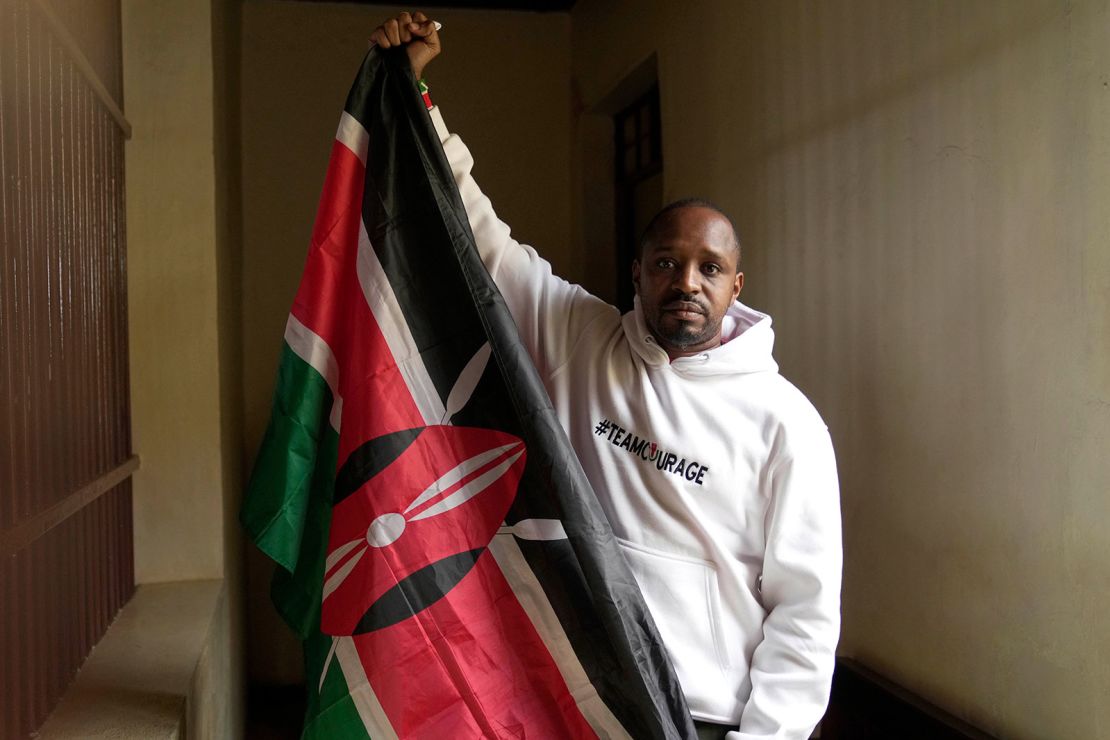 Prominent Kenyan activist Boniface Mwangi poses for a photo while holding a Kenyan flag inside the dock at Kahawa Law Courts in Kiambu, Kenya, Monday, July 21, 2025.