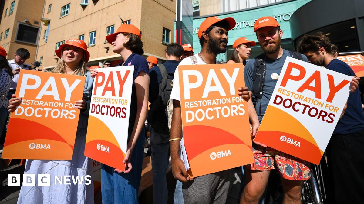 Resident doctors on strike hold orange placards saying 'pay restoration for doctors' with the BMA logo on them outside Bristol Royal Infirmary on Friday.