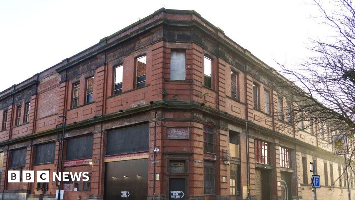 An aerial view of Forth Yard in Newcastle. The land stands between the River Tyne and the green Utilita Arena. The land is covered in sparse grass and dirt tracks.