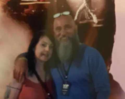 Tracey Baldwin Man and woman smiling in front of an Elvis poster