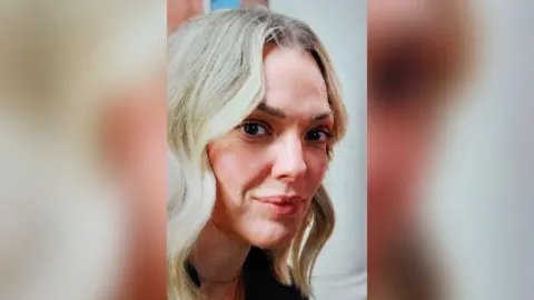 Portrait image of Rachel Booth who has blonde tresses and light brown eyebrows. She wears a light chain around her throat.