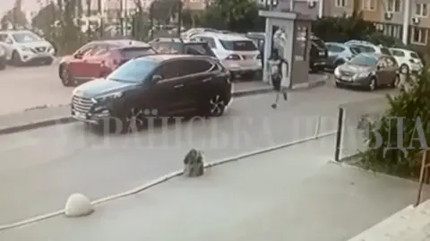 Reuters A man appearing to wear dark shorts and body armour is seen running in a car park in Kyiv.