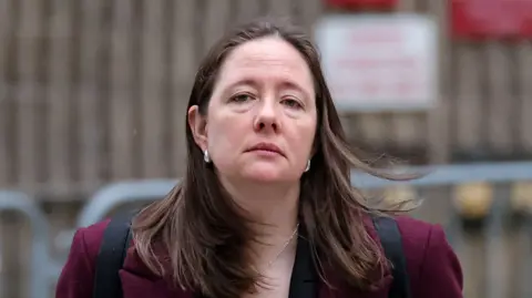 Reuters Maurene Comey wears a red jacket and has a blank expression
