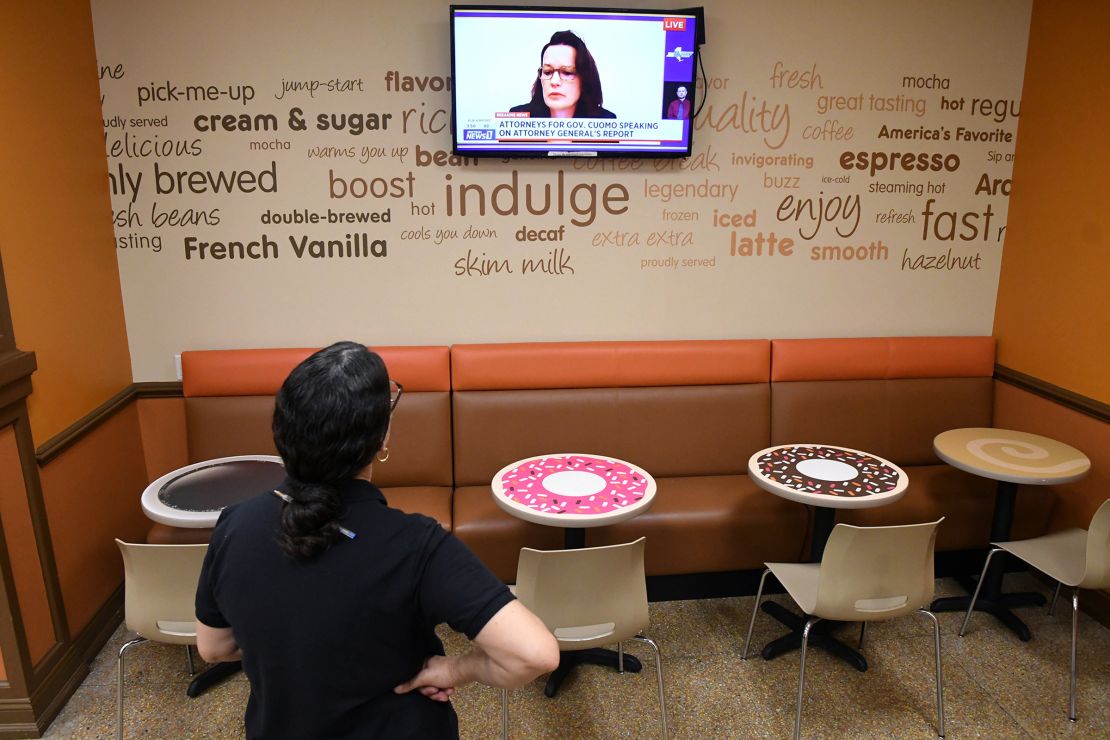In this August 2021 photo, a manager at Dunkin' Donuts watches Rita Glavin, attorney representing Governor Andrew Cuomo, speak during a press conference on television at the Capitol in Albany.