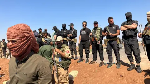 armed security forces on a berm across a road