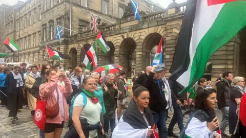 Protesters with Palestinian flags passing by the city chambers in Edinburgh.