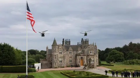 Reuters a small castle building beside a us a flag as two military helicopters fly overhead