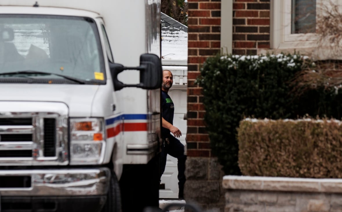 Photo shows someone entering the side door of the home of Nicholas Cartel and Singa Bui behind a Toronto police cube truck.