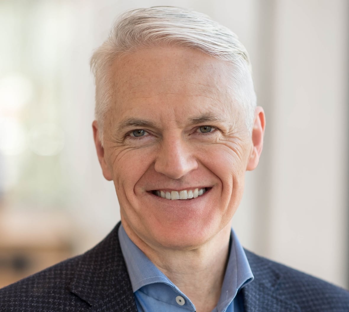 A man in a blazer smiling. 