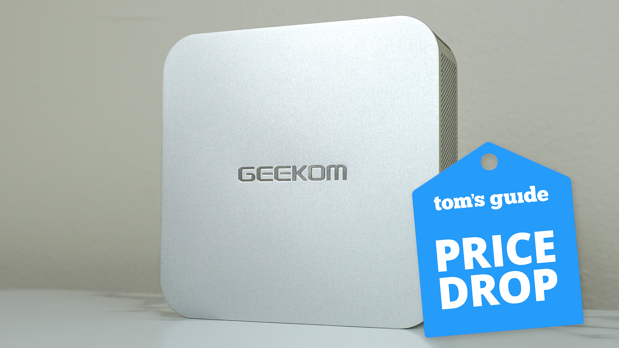 Geekom A6 on a desk with a Tom's Guide Price Drop deals badge on top