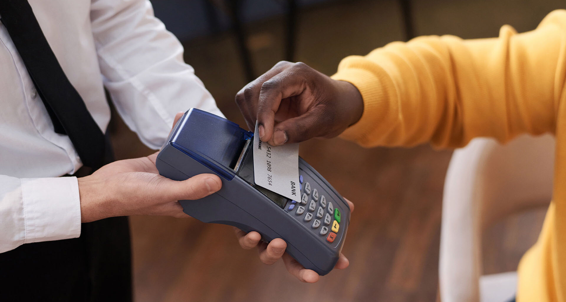 A server holding an EFTPOS machine while a customer uses their card to make a contactless payment.