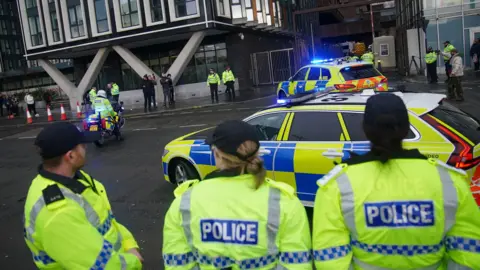PA Media Police officers watching as police escort a prison van