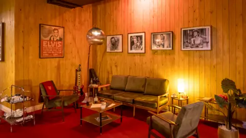 Graham Turner A room with green sofas and Elvis posters on the wall