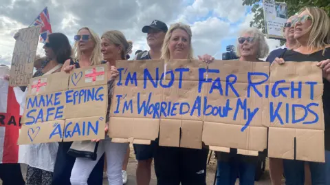 PA Media line of women holding a hand made cardboard banner saying "I'm not far right, I'm worried about my kids"