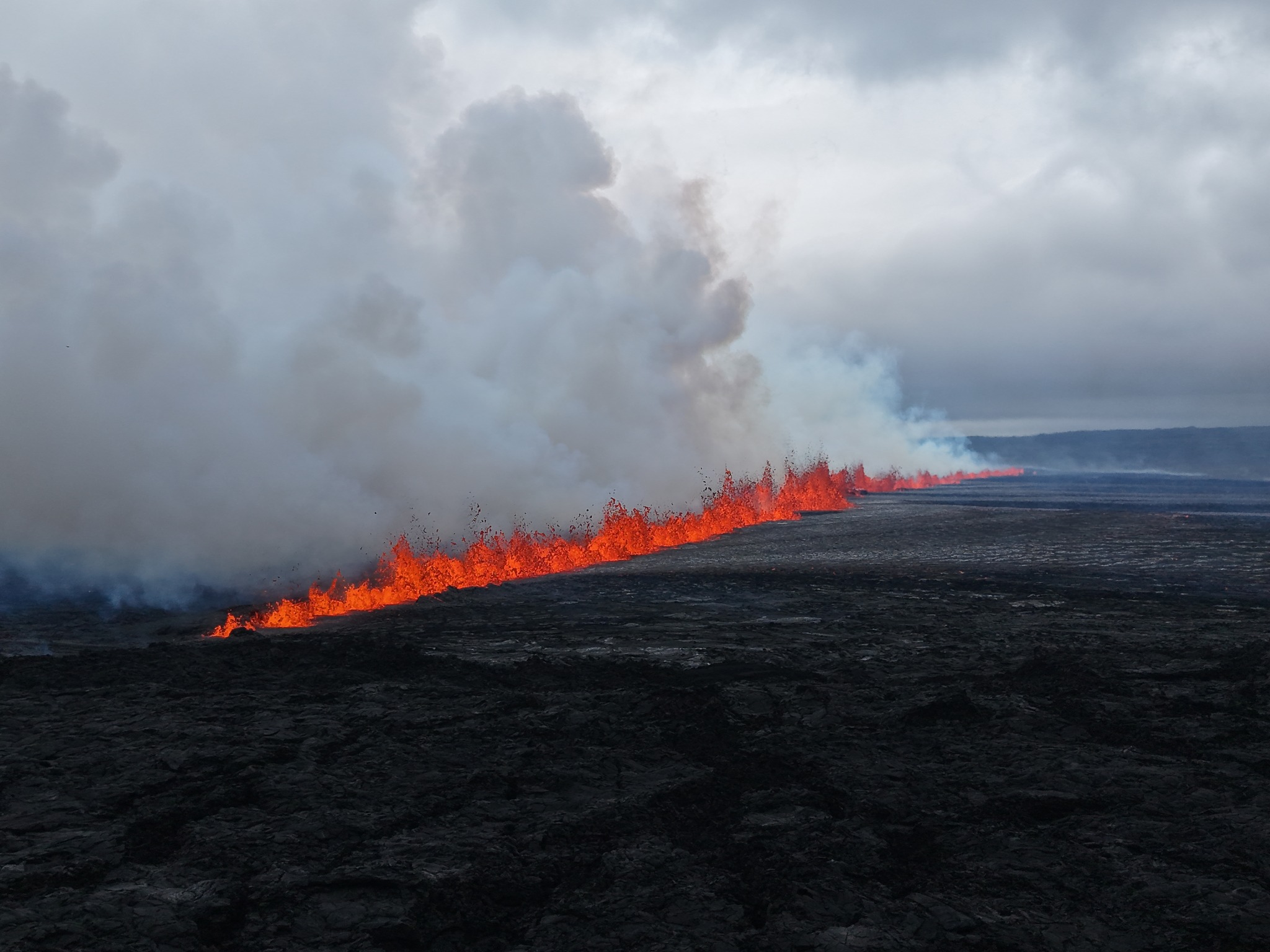 A photograph of lava erupting in a line at the Sundhnúkur crater row fissure.