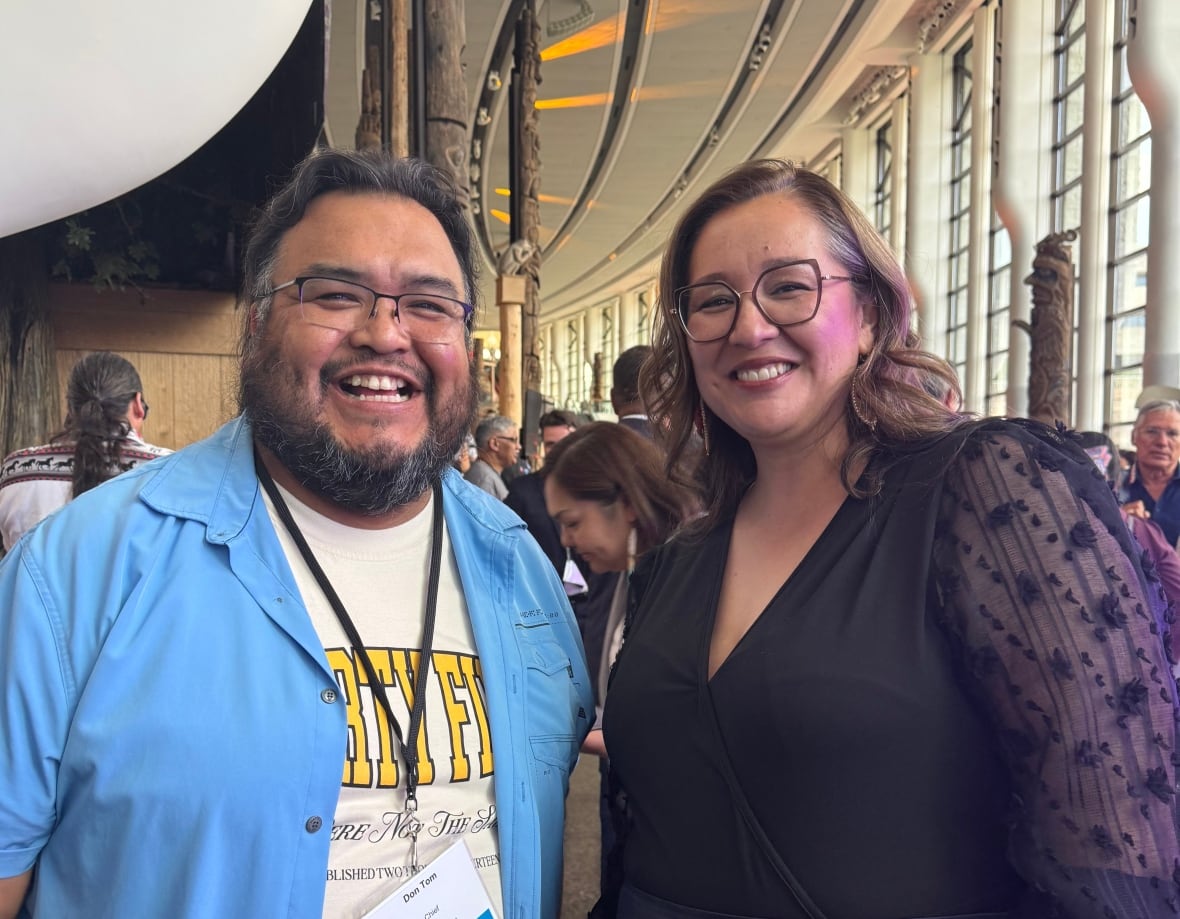 A man and woman pose for a photo smiling into the camera.