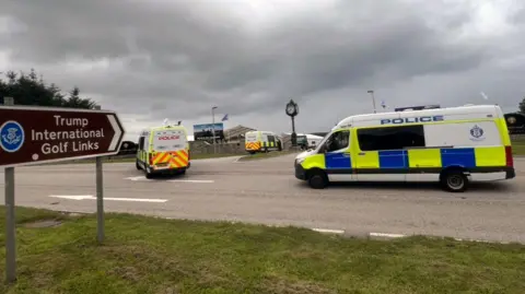 BBC Three police vans passing a roundabout near the Trump International Golf Links in Ayrshire.