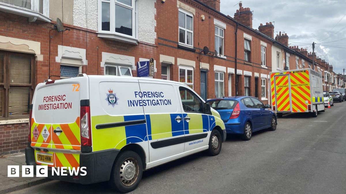 Police vehicles on Wolverton Road with terraced houses behind the vehicles