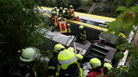 Thomas Warnack/ dpa An overturned train carriage is attended by emergency service personnel