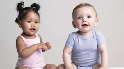 Getty Images A baby girl in a  pink baby grow and and baby boy in a blue baby grow