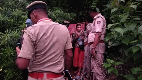 Karnataka police Policemen talking to the Russian woman who stands outside her cave dwelling 