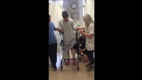 Family handout Ed Caudwell at the hospital after his accident being assisted by staff on a walker.