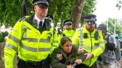 EPA Police officers carry a person in handcuffs away from Parliament Square