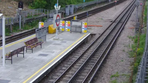 David Howard via Flickr Colindale station platform as seen from above shows Tube roundel, wooden benches and train tracks
