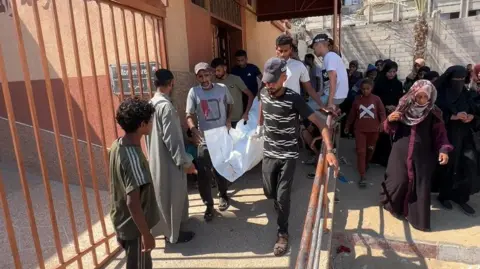 Men carry the body of Mary Sheikh al-Eid at Nasser Hospital, in Khan Younis, southern Gaza (25 July 2025)