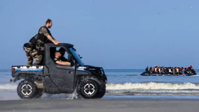 French gendarmes drive a buggy as migrants catch a boat on the French coast