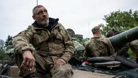 Getty Images Exhausted Ukrainian soldiers sit on a tank