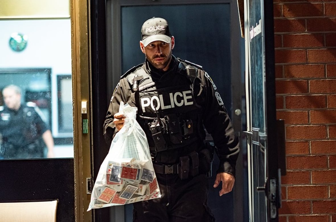 A police officer holds a bag of playing cards and cash.