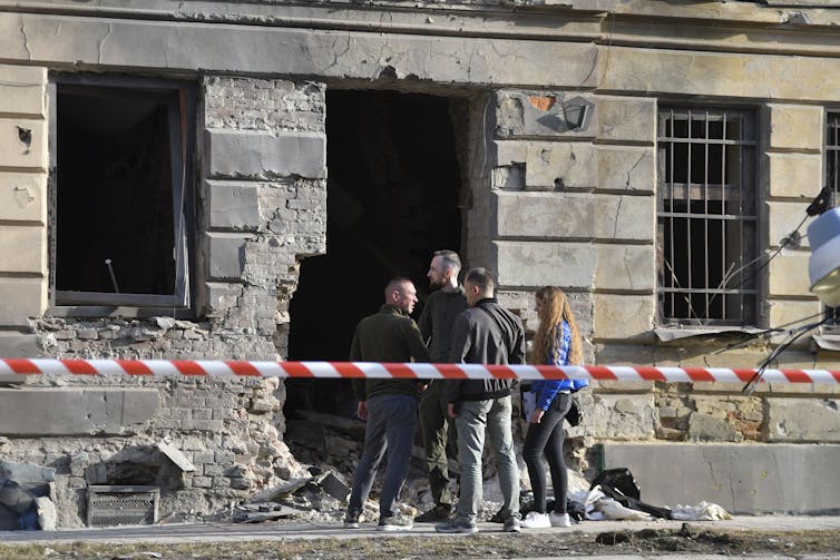 People stand near the site of a drone strike on a residential building in Ukraine.