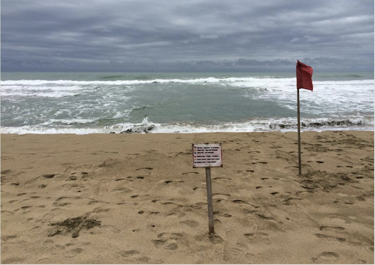 signs on a beach; dark water among ocean waves