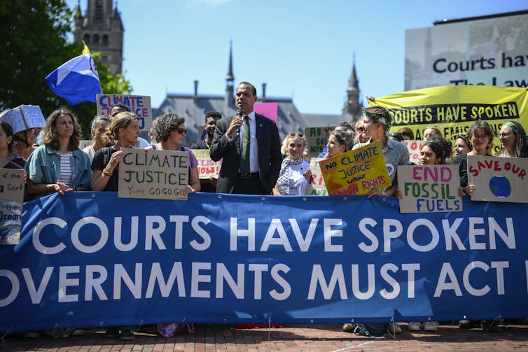 man giving speech in front of demonstration.
