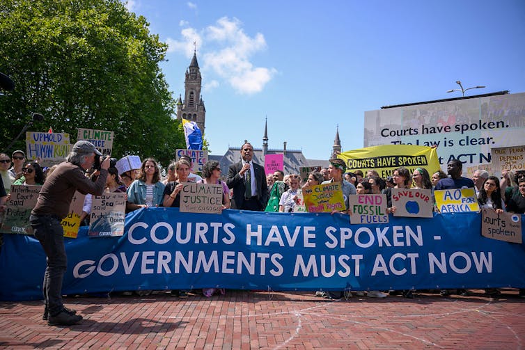 People gather behind a banner reading 'courts have spoken – governments must act now'