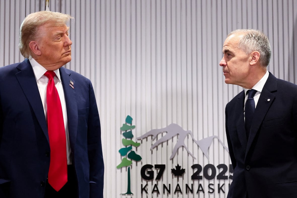 Two men in suits and ties appear in conversation as they look at one another.  