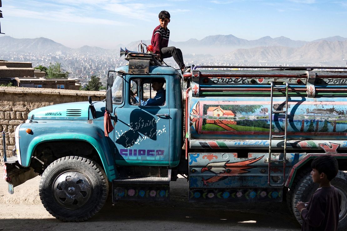 An Afghan boy sits atop a potable water tanker on a hillside in Kabul on April 27, 2025.
