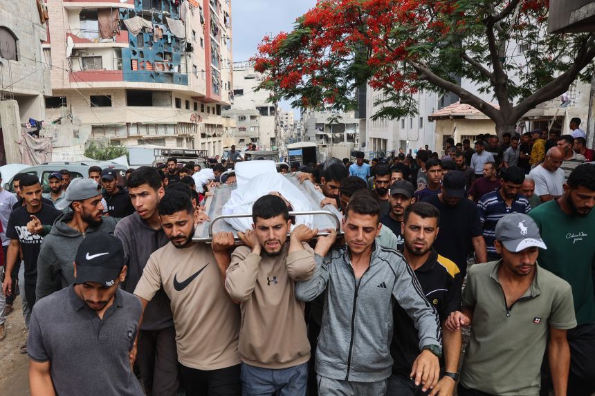Palestinians carry the body of a man killed while attempting to get aid at a distribution point in Gaza, on June 23.