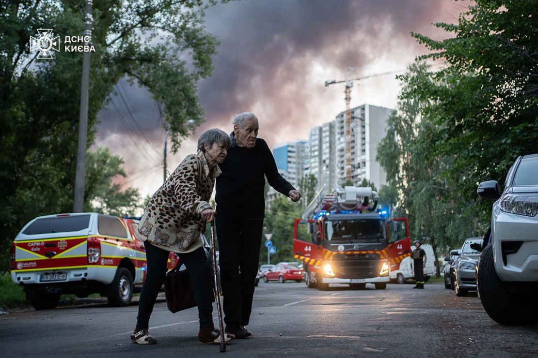 Residents move away from the scene after a Russian airstrike in Kyiv on Friday.