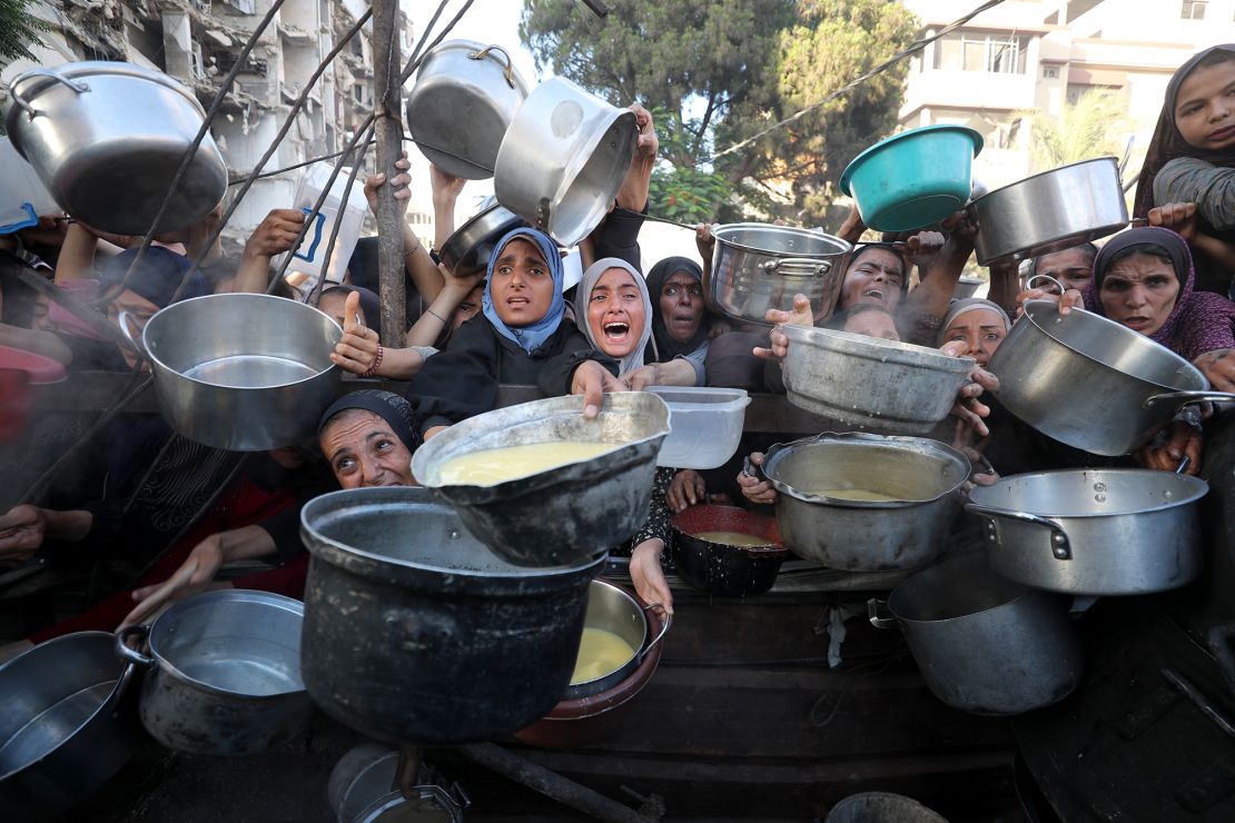 Palestinians, including children struggle to receive hot meals distributed by a local charity in Gaza City on July 14.