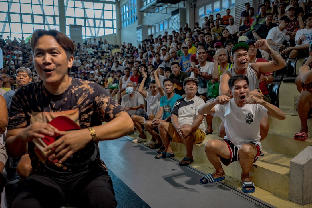 Fans react as they watch a broadcast of Manny Pacquiao's fight against Mario Barrios boxing match at a school gymnasium.