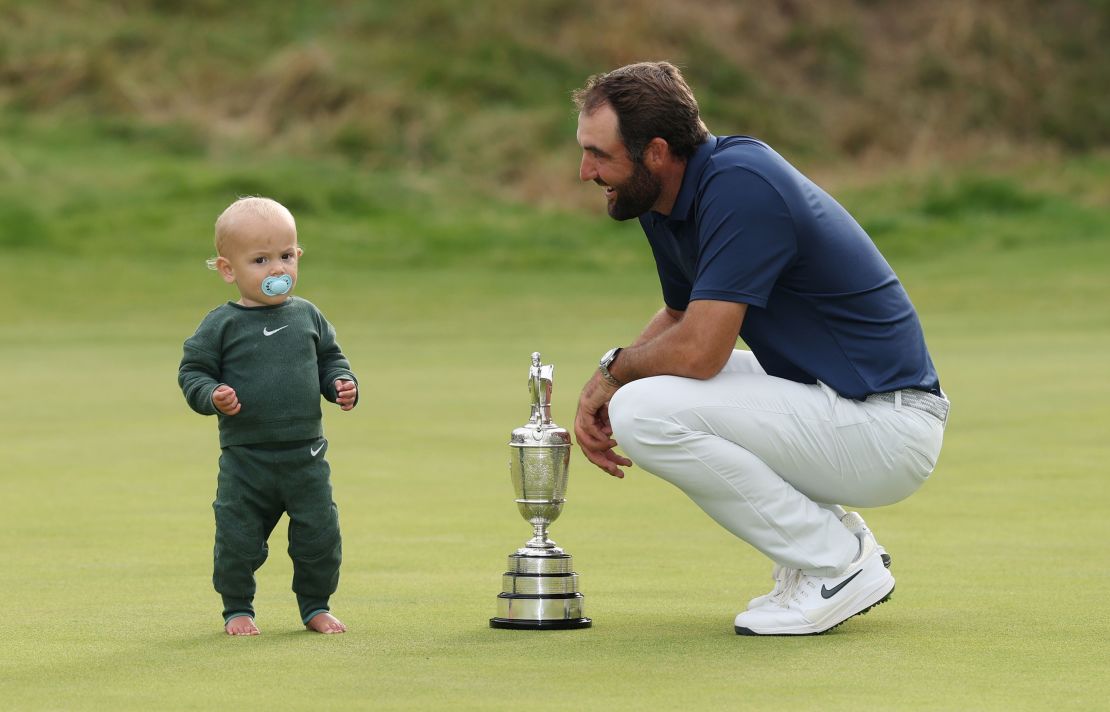 Scottie Scheffler with his son Bennett Scheffler and the Claret Jug on the 18th green after winning.