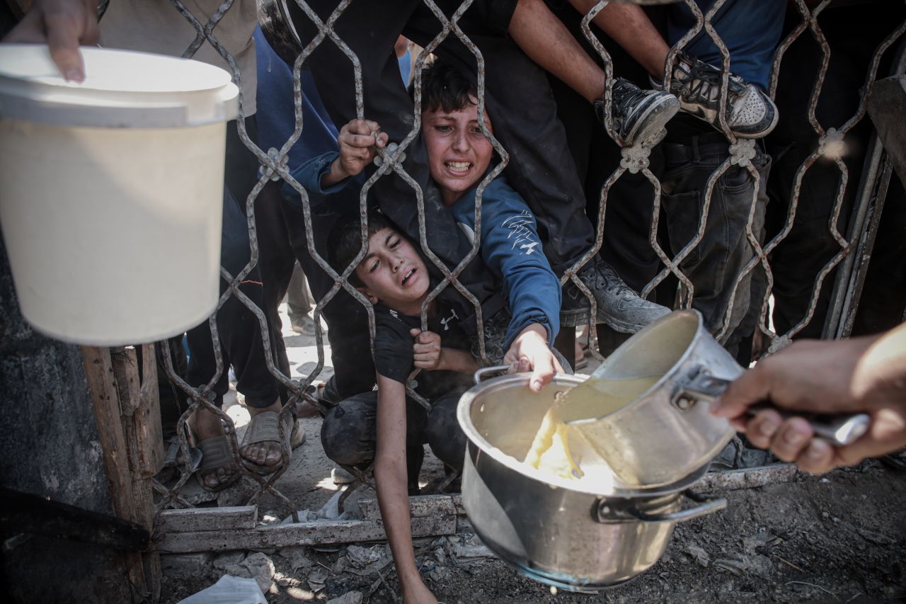 Palestinians struggling with hunger wait for hours under the scorching heat to receive food aid in Gaza City on Sunday.