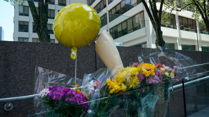Flowers and a balloon reading ‘Love one another’ are left outside the 345 Park Avenue building