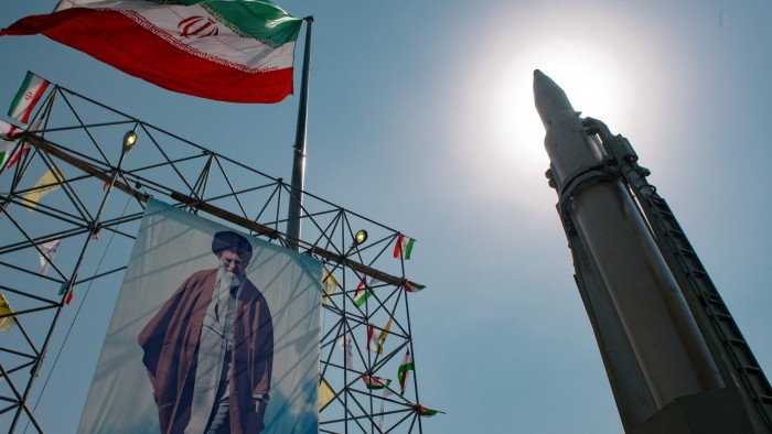 A large banner featuring Iran's Supreme Leader Ayatollah Ali Khamenei is displayed next to a ballistic missile in Baharestan Square, Tehran.