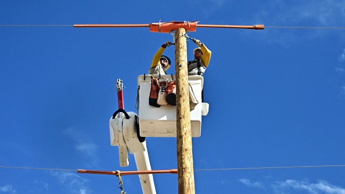 A utility crew installs utility poles for power lines bringing electricity to residents in Arizona