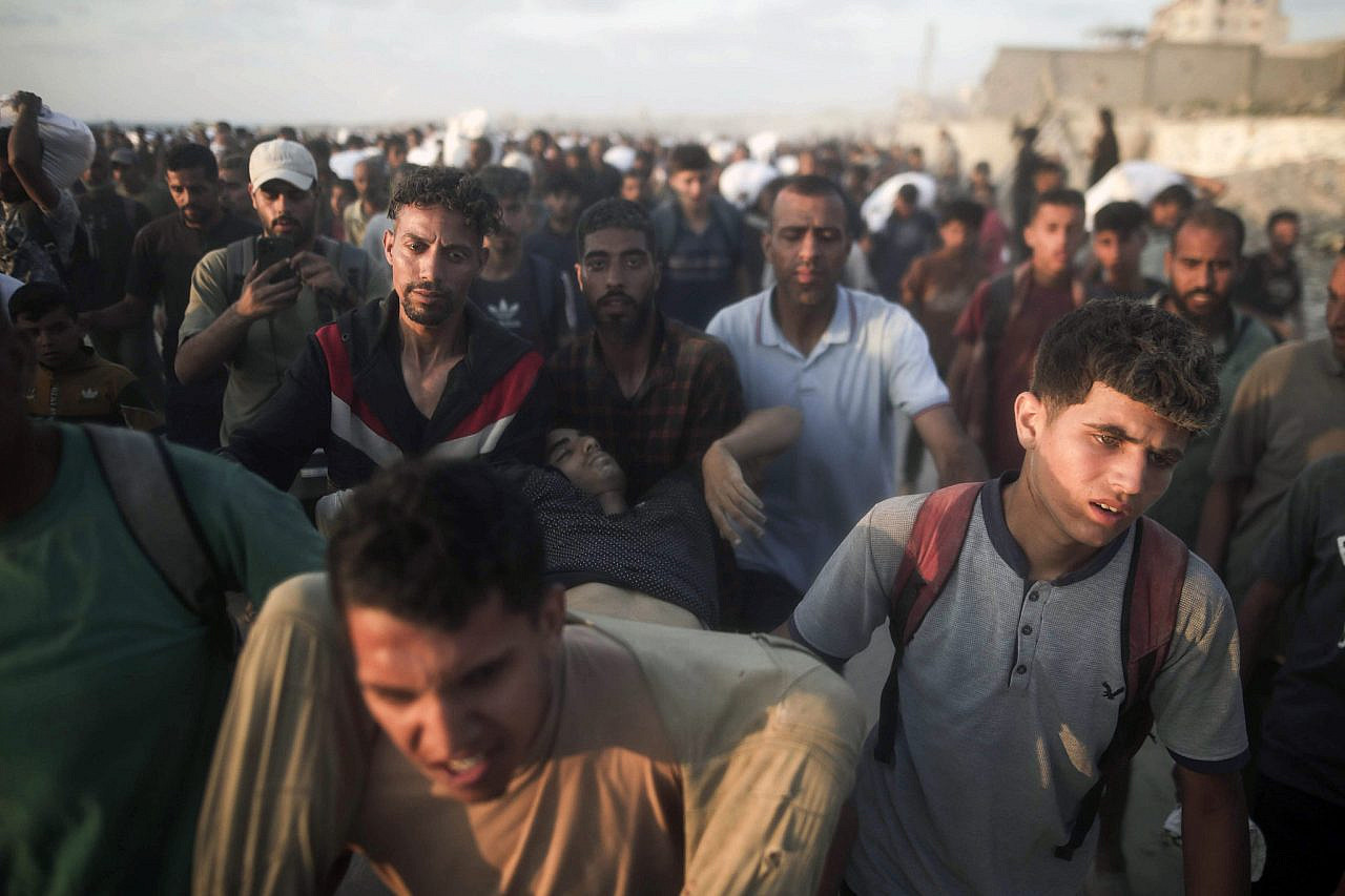Palestinians carry away a wounded man hit by Israeli fire while trying to get food aid on Al-Rashid Street, northern Gaza City, June 16, 2025. (Yousef Zaanoun/ActiveStills)